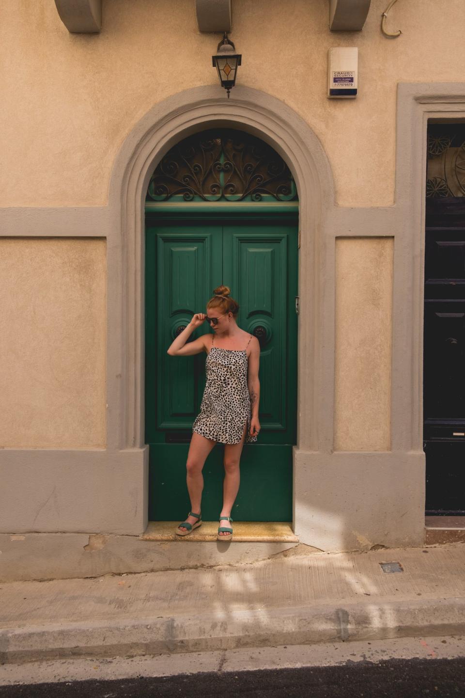 Girl in dotty dress stood in front of a green arched doorway