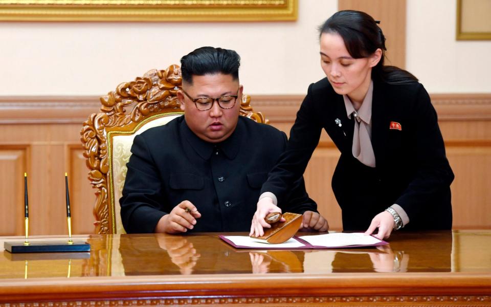 Kim Yo-jong, right, sister of North Korean leader Kim Jong-un, helps Kim sign joint statement - AP
