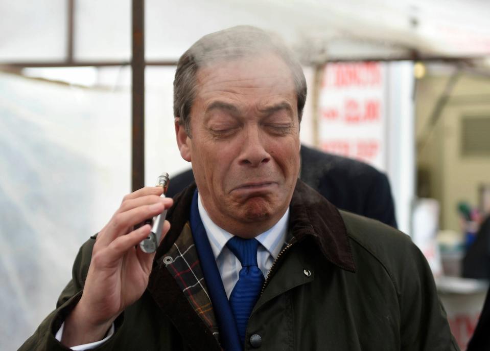 Brexit Party leader Nigel Farage coughs as he samples a Pinkman flavoured e-cigarette during a Brexit Party walkabout in Lincoln, England, Friday May 10, 2019. (Joe Giddens/PA via AP)