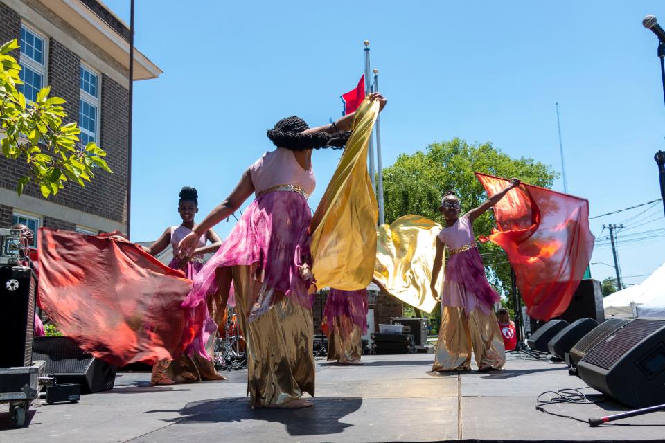 Restoration dance team members perform with orange and yellow flags on Saturday, June, 18, 2022, during the Juneteenth festival held at Bradley Academy Museum and Cultural Center.