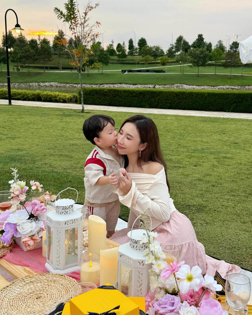 Jasmine Yongs son kisses her on the cheek on a picnic blanket outside  (@jasmine.y____ via Instagram)