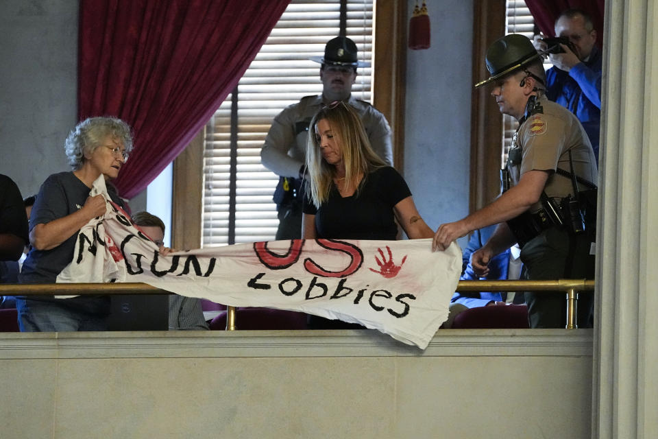 A Tennessee State Trooper, right, removes a demonstrator's banner advocating for gun law reform from the House chamber during a special session of the state legislature on public safety, Monday, Aug. 28, 2023, in Nashville, Tenn. (AP Photo/George Walker IV)