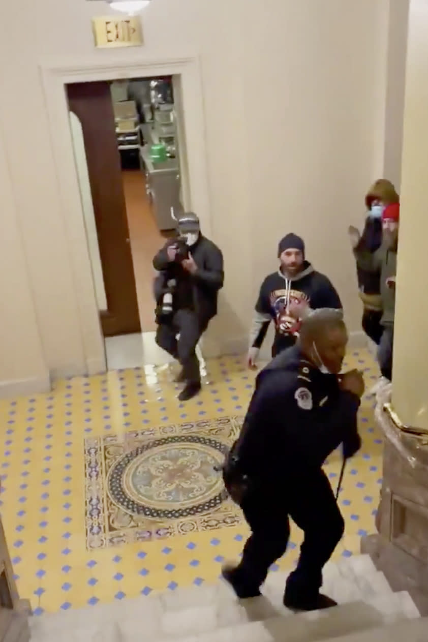 In this image made from video and provided by HuffPost, Capitol Police Officer Eugene Goodman calls for backup as an angry mob gives chase inside the U.S. Capitol in Washington on Jan. 6, 2021. One bright spot in all the chaos and anger from the mob siege at the U.S. Capitol was Goodman confronting a mob and retreating, risking his life to perhaps save the U.S. Senate. (Igor Bobic/HuffPost via AP)