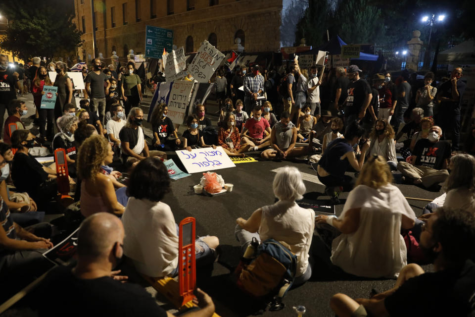 Demonstrators sit during a protest in front of Israel's Prime Minister's residence in Jerusalem, Thursday, July 16, 2020. Hundreds of protesters gathered outside Netanyahu's official residence in Jerusalem to protest against corruption and vent their anger at the economic downtown. (AP Photo/Ariel Schalit)