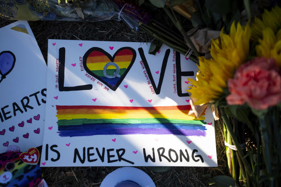 The sun shines on a sign placed at a memorial outside of Club Q following Saturday's fatal shooting at the gay nightclub, in Colorado Springs, Colo., Monday, Nov. 21, 2022. (AP Photo/ Parker Seibold)