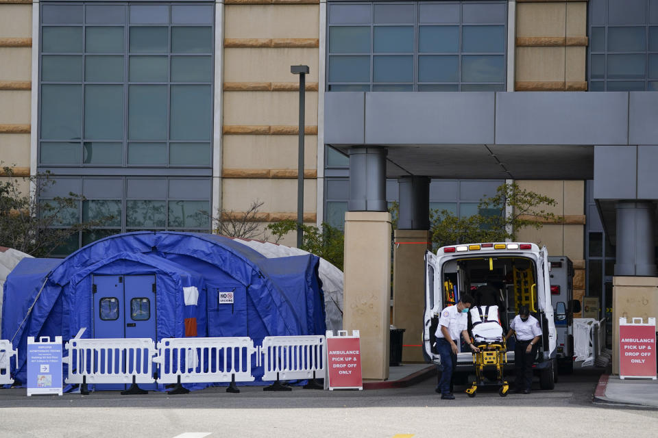 Fotografía del jueves 17 de diciembre de 2020 de trabajadores médicos retirando una camilla de una ambulancia cerca de carpas médicas erigidas afuera de la sala de emergencias del UCI Medical Center en Irvine, California. (AP Foto/Ashley Landis, Archivo)