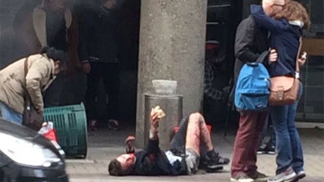 A survivor lies on the ground as a couple nearby embraces. Photo: Twitter