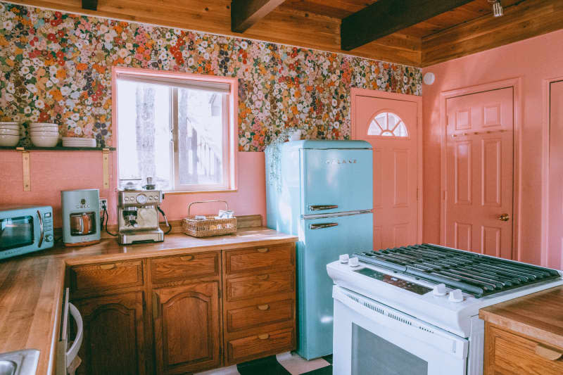 kitchen with peach backsplash and doors, wood ceiling, floral wallpaper, and lots of wood