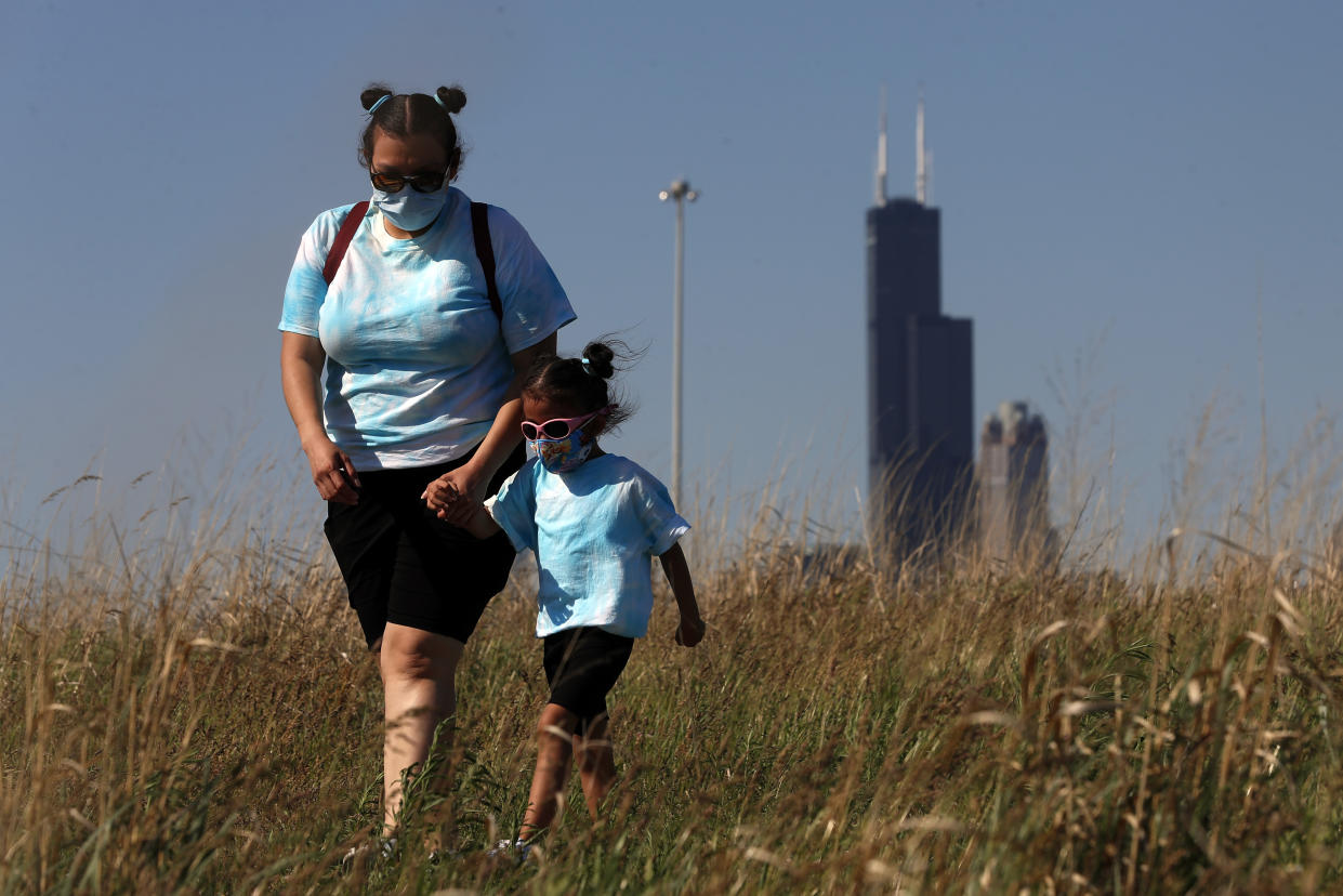 A mother walks with her daughter wearing face masks in Chicago's Henry C. Palmisano Nature Park, Friday, June 4, 2021. (Shafkat Anowar/AP)
