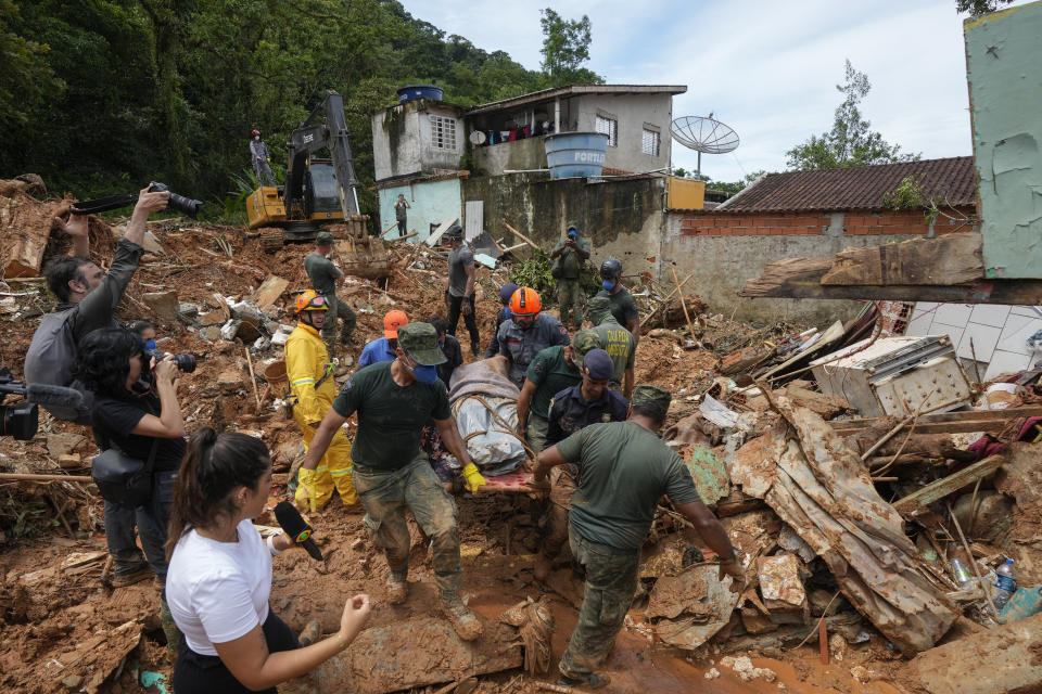 Rescue workers and volunteers carry the body of a landslide victim near Barra do Sahi beach after heavy rains in the coastal city of Sao Sebastiao, Brazil, Wednesday, Feb. 22, 2023. (AP Photo/Andre Penner)