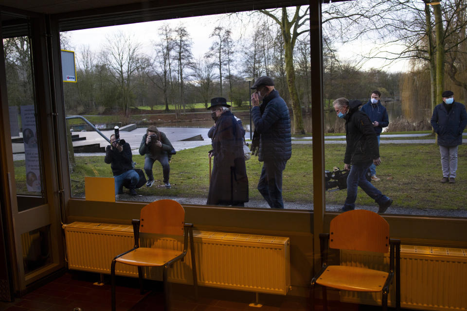 Okko Molenkamp, 94, center left with black hat, is filmed and photographed as he walks to the entrance of a COVID-19 vaccination facility in Apeldoorn, Netherlands, Tuesday, Jan. 26, 2021. Dutch authorities began vaccinating the first of thousands of people aged over 90 years who still live at home. (AP Photo/Peter Dejong)
