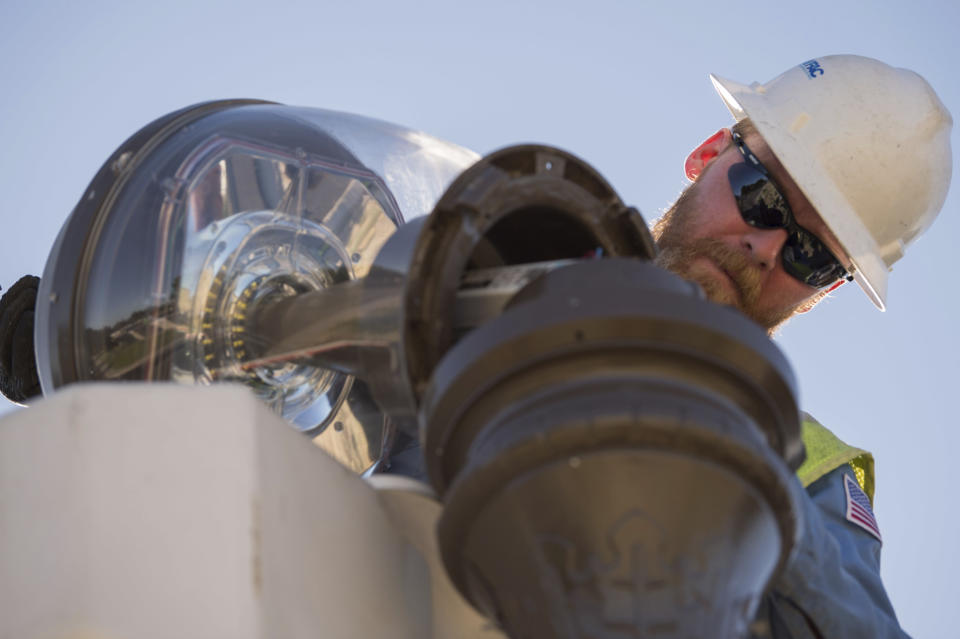 In this July 18, 2019 photo provided by the U.S. Navy, Tim Goodwin, a high-voltage electrician with Naval Facilities Engineering Command (NAVFAC), repairs a street lamp on Naval Air Weapons Station China Lake, Calif. The base sustained heavy earthquake damage that experts estimate will cost over $5 billion to repair. (Mass Communication Specialist 3rd Class Jeffery L. Southerland/U.S. Navy via AP)