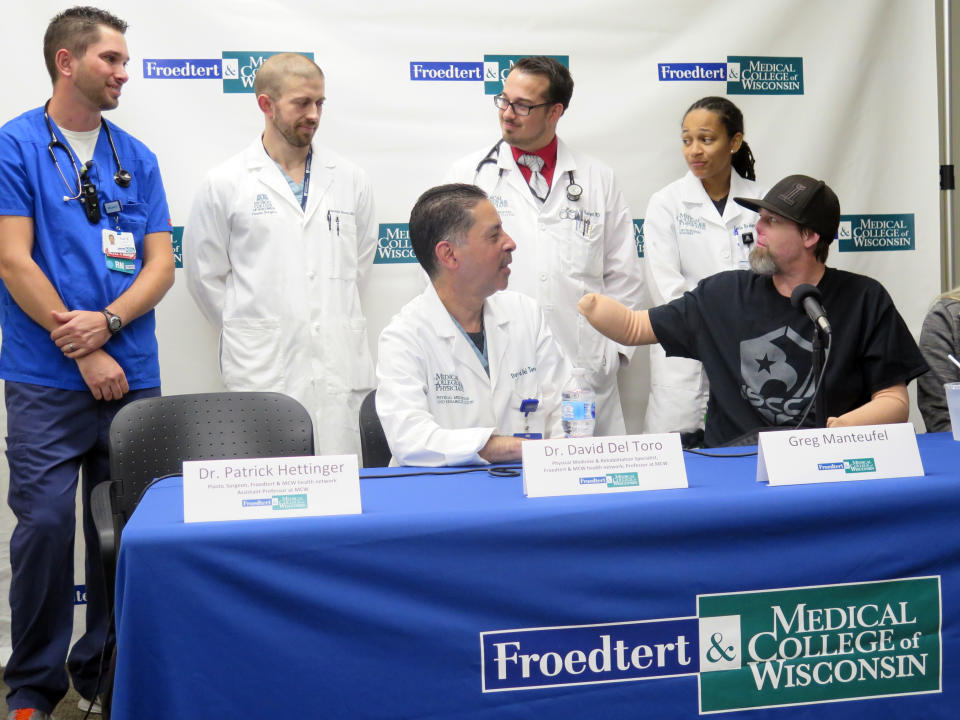 Greg Manteufel, right, points to nurse Paul Moran, far left, on Tuesday, Oct.2, 2018, in Milwaukee, to express his gratitude for his care at Froedtert & the Medical College of Wisconsin. Manteufel spoke about his recovery from a rare blood infection that led to the amputation of part of his forearms and legs. Doctors say the blood infection was caused by dog saliva. (AP Photo/Ivan Moreno)