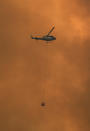 A helicopter drops water on a homestead as bushfires impact on farmland near the small town of Nana Glen, some 600kms north of Sydney on November 12, 2019. - Bushfires reached within kilometres (miles) of Sydney's city centre prompting firefighting planes to spray red retardant over trees and houses in a northern suburb. (Photo by WILLIAM WEST / AFP) (Photo by WILLIAM WEST/AFP via Getty Images)