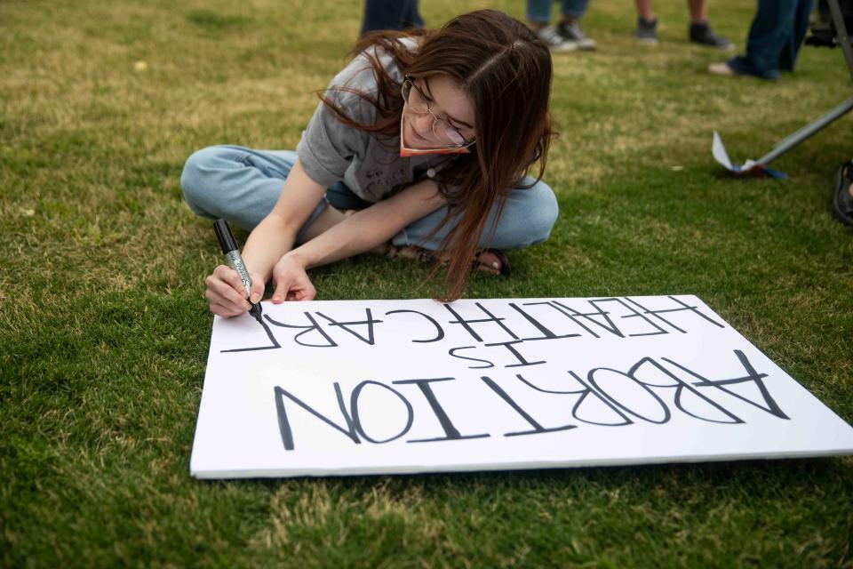 Devin Narveson writes, “Abortion is Healthcare,” on a large sign while abortion-rights advocates gather at Albert Johnson Park near City Hall in Las Cruces, N.M. to protest after a leaked draft opinion showed that the Supreme Court voted to strike down Roe v. Wade on Tuesday, May 3, 2022.