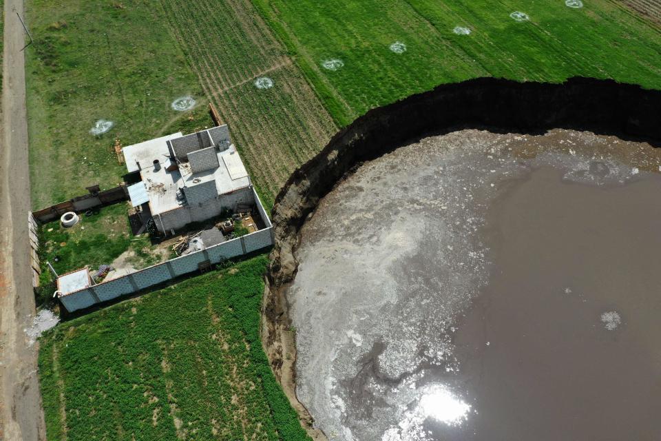 Aerial view of a sinkhole nearing a house in a farmland in Santa Maria Zacatepec, state of Puebla, Mexico (AFP via Getty Images)