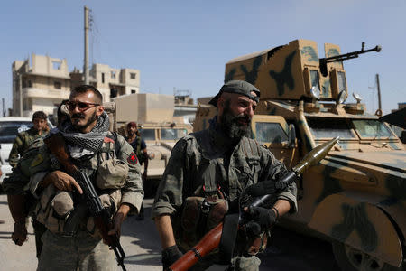 FILE PHOTO: A fighter of the Syrian Democratic Forces (SDF) carries a weapon as he stands near a military vehicle in Raqqa, Syria, October 16, 2017. REUTERS/Rodi Said/File Photo