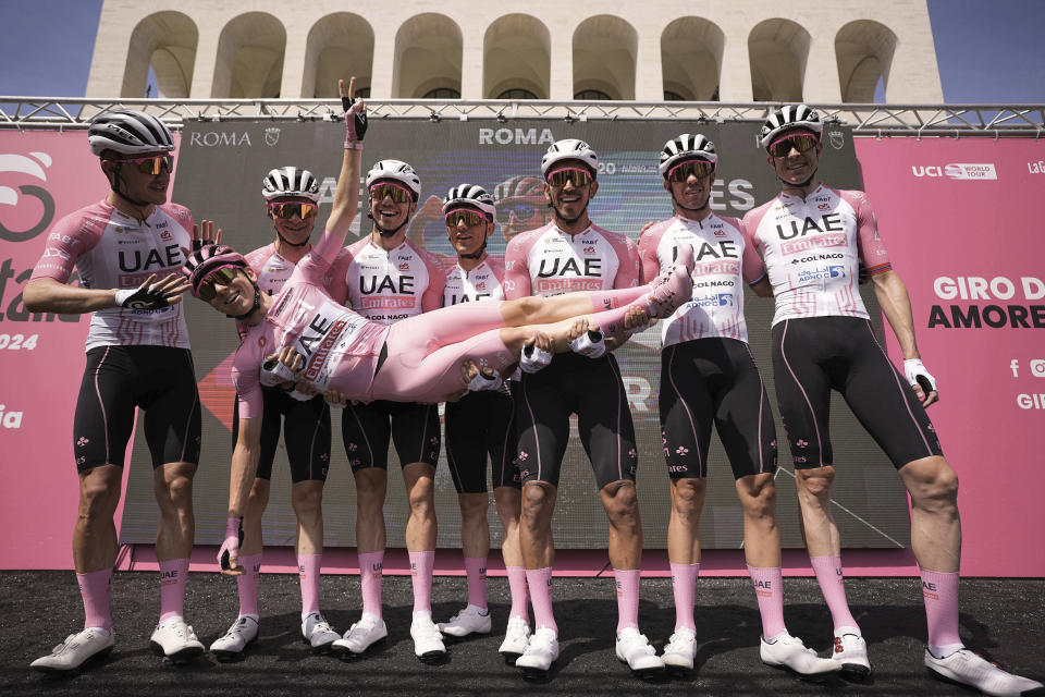 Slovenia's Tadej Pogacar, wearing the pink jersey of the race overall leader, is lifted in celebration by teammates ahead of the start of the final stage of the Giro d'Italia cycling race, in front of the Palazzo della Civilta' Italiana, also known as Colosseo Quadrato (Square Colosseum) in Rome, Sunday, May 26, 2024. (Marco Alpozzi/LaPresse via AP)