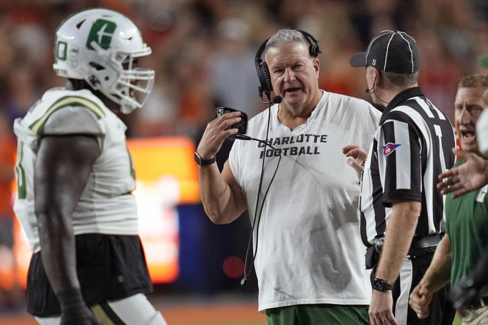 Charlotte coach Biff Poggi, center, talks with an official during a timeout in the first half of the team's NCAA college football game against Florida, Saturday, Sept. 23, 2023, in Gainesville, Fla. (AP Photo/John Raoux)