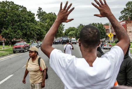 Protestors hold their hands up as police approach them on Page Ave. after a shooting incident in St. Louis, Missouri August 19, 2015. REUTERS/Lawrence Bryant