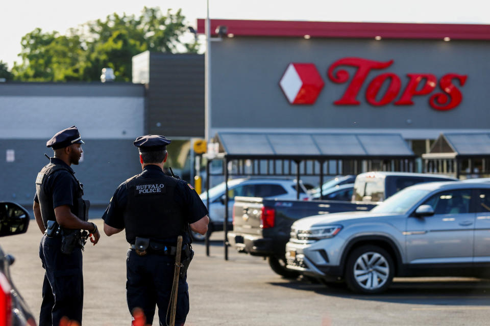 Two police officers are stationed outside the Tops supermarket.