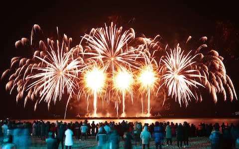 Residents and tourists watch the New Year's Eve fireworks show at Yulpo Beach in South Korea - Credit: REX