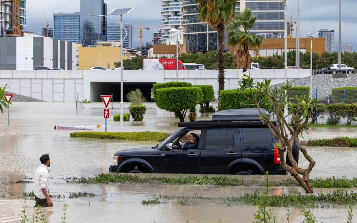 A motorist waits while attempting to navigate flood waters in the Dubai Sports City district