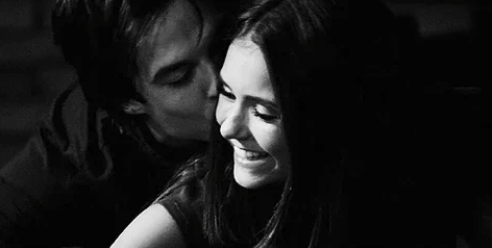 Ian Somerhalder kisses Nina Dobrev's cheek while she smiles, both appearing happy in a candid moment