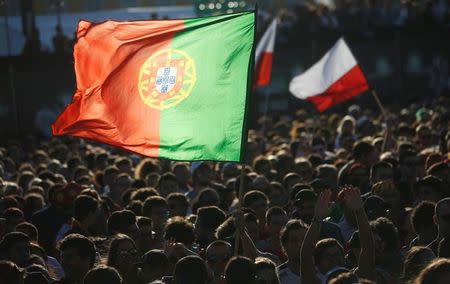 Fans hold Portuguese and Polish flags before they watch the Euro 2016 soccer match between Portugal and Poland at a public screening in downtown Lisbon, Portugal, June 30, 2016. REUTERS/Rafael Marchante