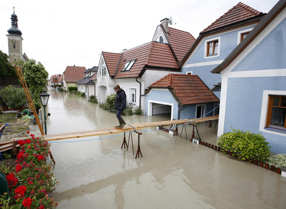 Una mujer cruza un puente artesanal en una calle inundada en Unterloiben, Austria, este 4 de junio de 2013