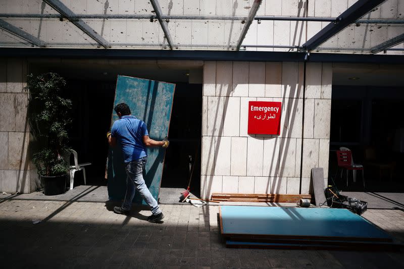 A man fixes damages at the Saint George Hospital University Medical Center after a massive blast in Beirut's port area