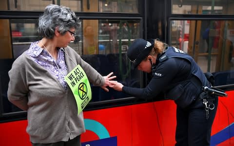 A police officer tries to remove the hand of protester Diana Warner, glued to a train - Credit: Dylan Martinez/Reuters