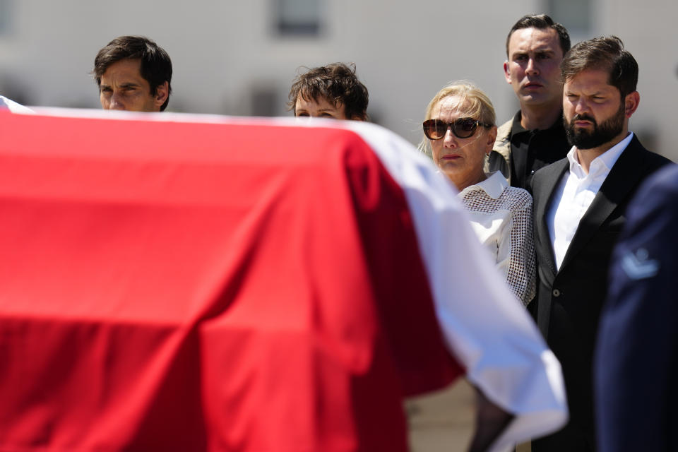 Cecilia Morel, the widow of former Chilean President Sebastian Pinera, and Chilean President Gabriel Boric, right, stand by Pinera's coffin after it arrived at the airport in Santiago, Chile, Wednesday, Feb. 7, 2024. The two-time former president died Feb. 6 in a helicopter crash. He was 74. (AP Photo/Esteban Felix)