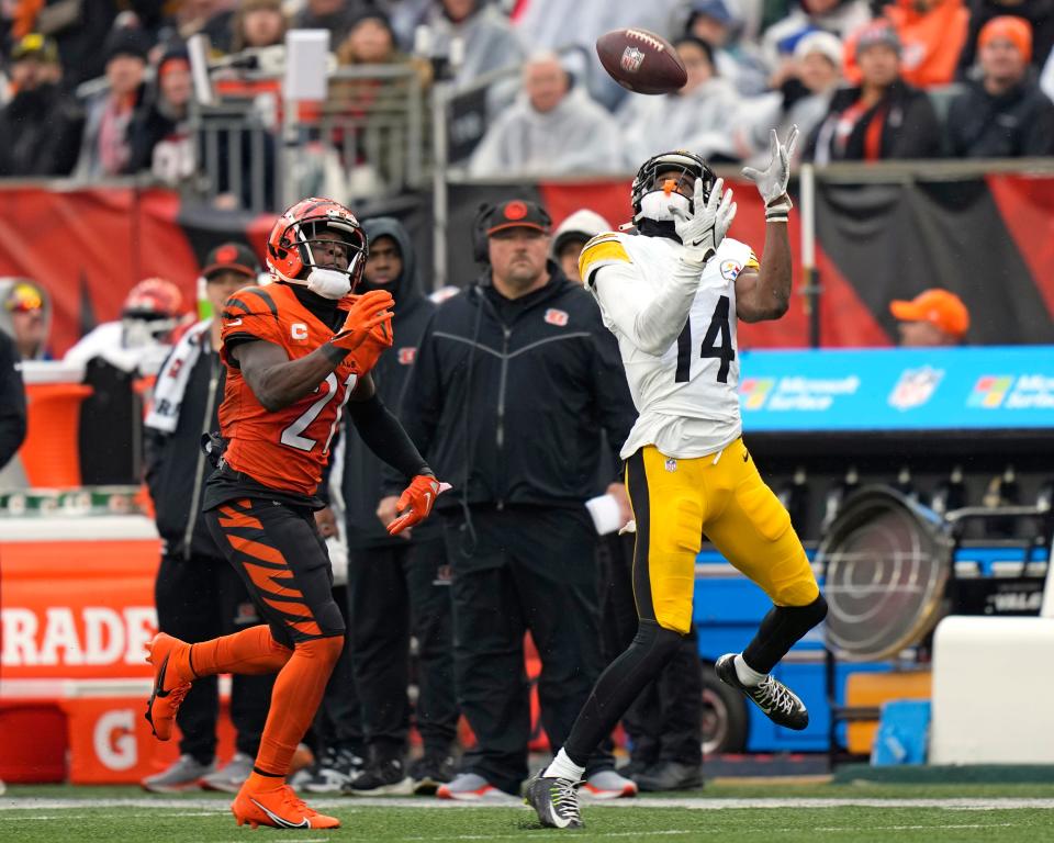 Pittsburgh Steelers wide receiver George Pickens (14) runs a pass by Kenny Pickett with Cincinnati Bengals cornerback Mike Hilton (21) defending during the second half of an NFL football game in Cincinnati, Sunday, Nov. 26, 2023. It was a 43-yard pass completion.
