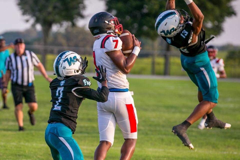 Dunnellon Chris Henry (7) grabs a pass with pressure from West Port Giovanni Wright (13) and West Port Jordon Honor (2) at West Port High School in Ocala, FL on Friday, August 25, 2023. [Alan Youngblood/Ocala Star-Banner]