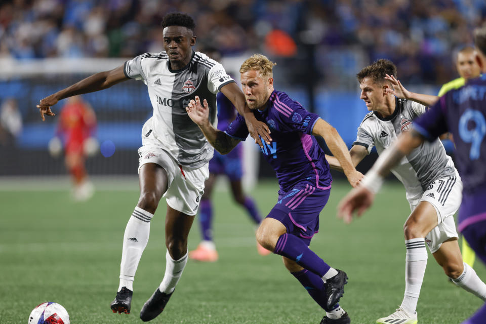 Toronto FC defender Aime Mabike, left, tries to hold back Charlotte FC midfielder Scott Arfield from the ball during the second half of an MLS soccer match in Charlotte, N.C., Wednesday, Oct. 4, 2023. (AP Photo/Nell Redmond)