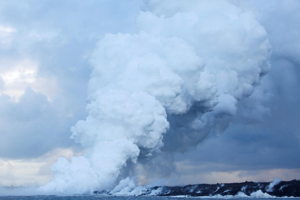 <p>A plume of laze, composed of steam, acid and volcanic glass, rises into the sky as lava flows into the Pacific Ocean in the Kapoho area, on the outskirts of Pahoa, during ongoing eruptions of the Kilauea Volcano in Hawaii, June 7, 2018. (Photo: Terray Sylvester/Reuters) </p>