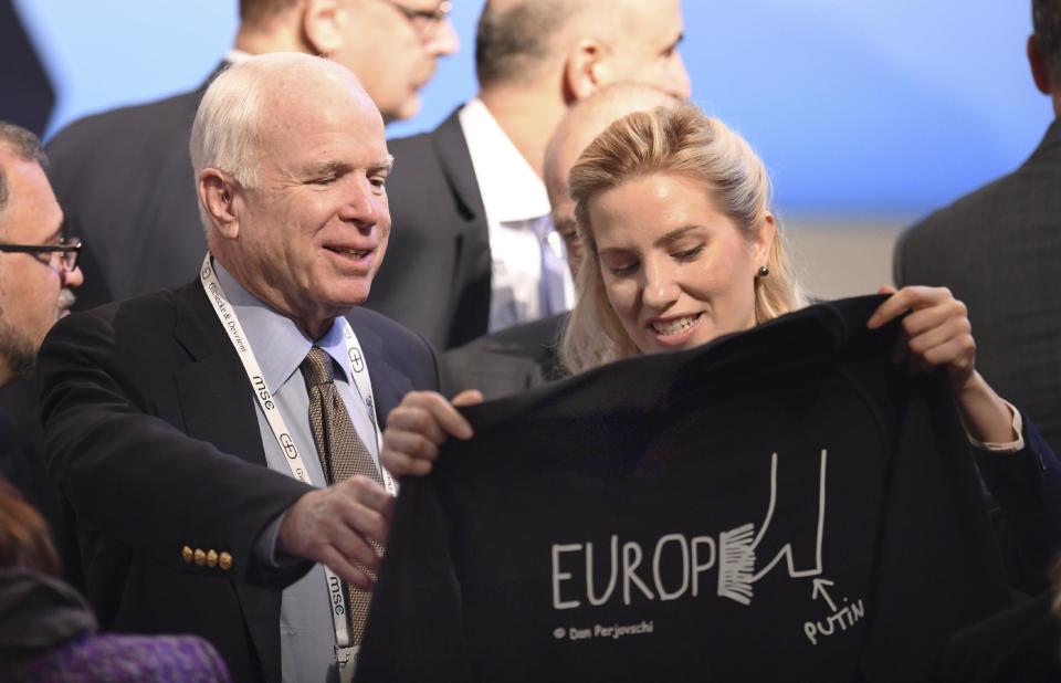 U.S. Senator John McCain, left, smiles as he get a t-shirt by Ukrainian journalist and politician Svitlana Zalishchuk on the last day of the Munich Security Conference in Munich, southern Germany, Sunday, Feb. 19, 2017. (Tobias Hase/dpa via AP)