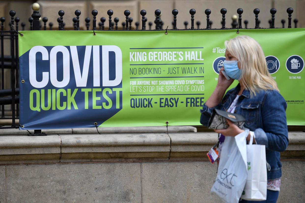 A person wearing a face covering walks past a sign for a walk-in Covid-19 testing centre in Blackburn on Wednesday (AFP via Getty Images)