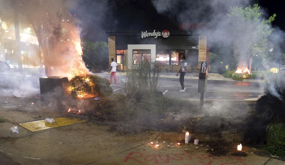 A Wendy's restaurant, background, burns Saturday, June 13, 2020, in Atlanta after demonstrators allegedly set it on fire. Demonstrators were protesting the death of Rayshard Brooks, a black man who was shot and killed by Atlanta police Friday evening following a struggle in the Wendy's drive-thru line. (Ben GrayAtlanta Journal-Constitution via AP)