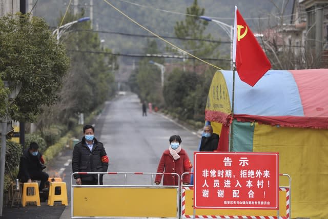 Volunteers stand beneath a Communist Party flag as they man a barricade checkpoint at a village in Hangzhou in eastern China's Zhejiang Province