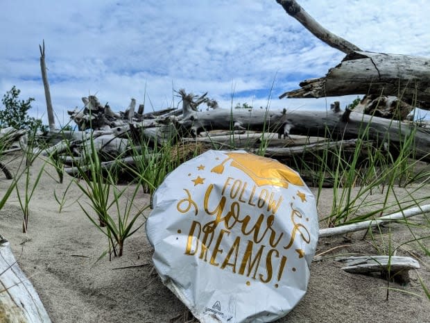 A half-deflated balloon marking someone's graduation lies in the sand on the north shore of Lake Erie.  (Submitted by Leanne Grieves - image credit)