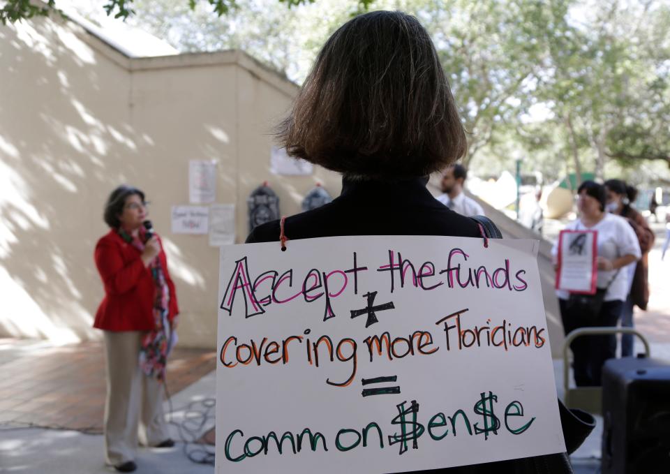 An activist wears a sign in support of Florida lawmakers expanding Medicaid during a protest in 2015 in Miami.