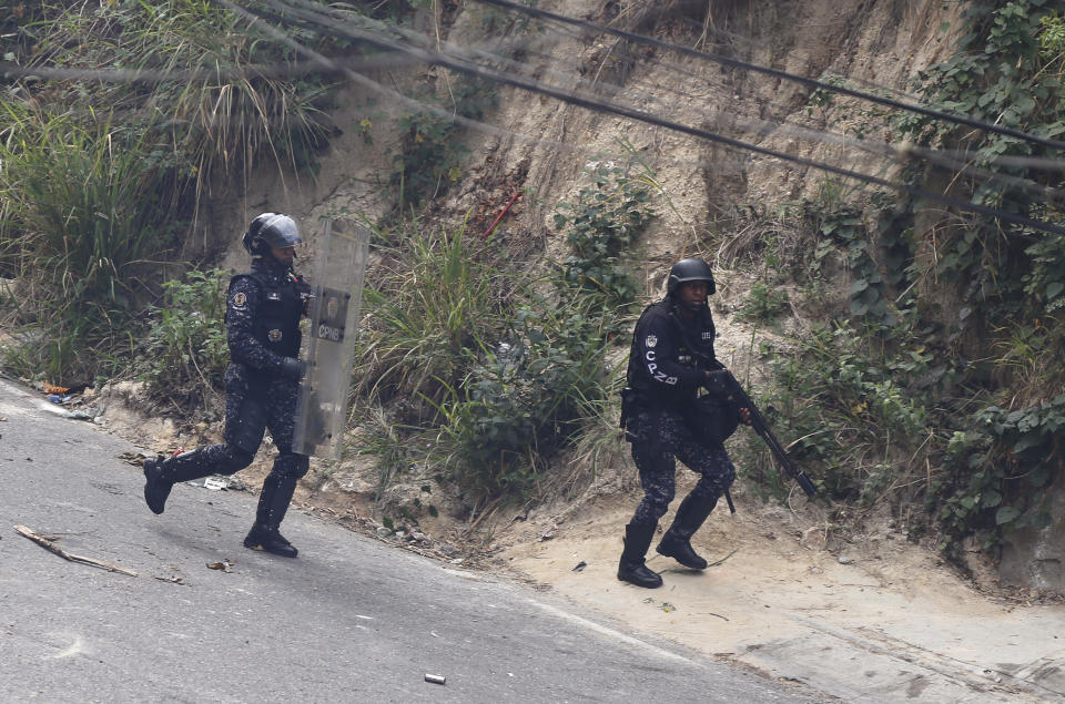 National Police work to disperse anti-government protesters shortly after a mutiny by a national guard unit in the Cotiza neighborhood of Caracas, Venezuela, Monday, Jan. 21, 2019. Security forces have fired tear gas against protesters in a poor neighborhood near the presidential palace after an apparent uprising by a national guard unit. (AP Photo/Fernando Llano)