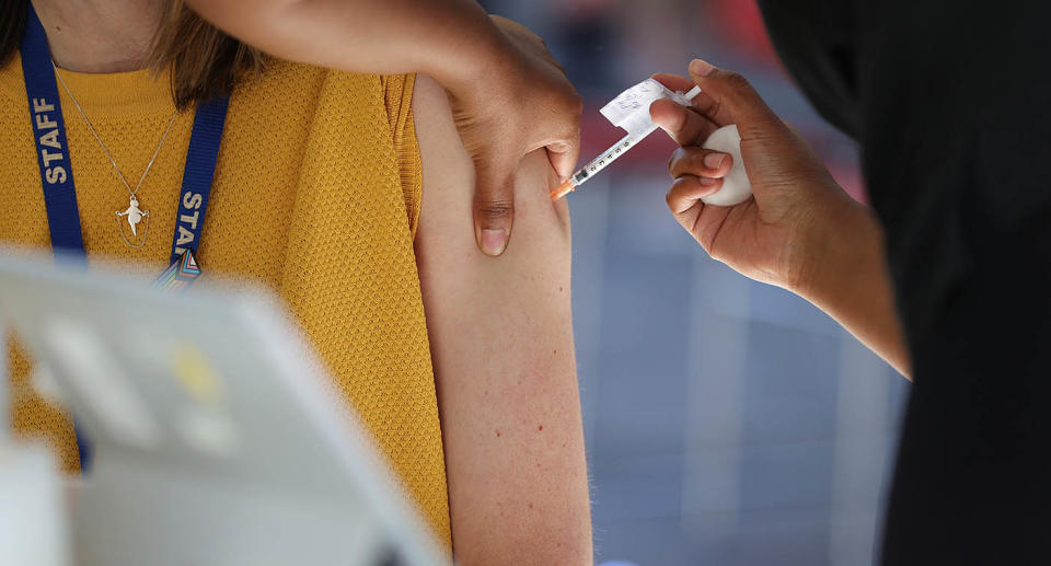 Should down photo of a woman receiving a Covid-19 vaccination.