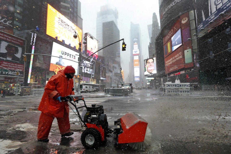 A worker clears slush from a street as snow falls Monday, Feb. 3, 2014, in New York's Times Square. Another winter storm bears down on the eastern U.S., only a day after temperatures soared into the 50s. (AP Photo/Jason DeCrow)