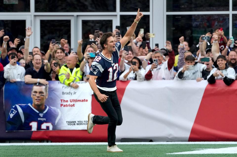 Former New England Patriots quarterback, Tom Brady, runs on to the field at Gillette Stadium on Sunday evening to welcome fans as the Patriots announce they will induct him into the Patriots Hall of Fame in June.