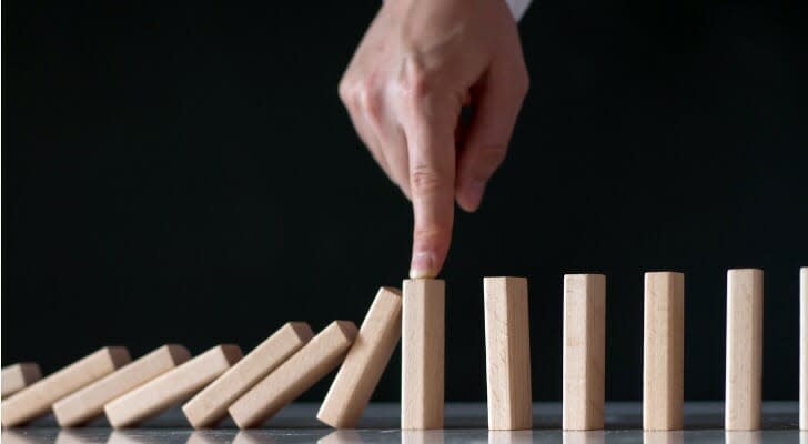 Man's hand keeps dominos from falling