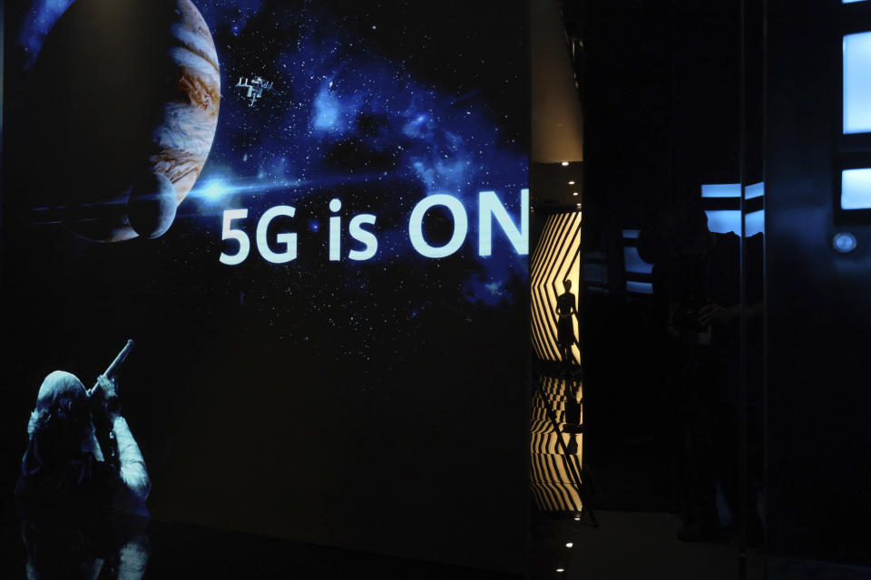 In this Aug. 19, 2019, photo, a guide is silhouetted in an exhibition promoting Huawei's 5G technologies at the Huawei Campus in Shenzhen in Southern China's Guangdong province. Facing a ban on access to U.S. technology, Chinese telecom equipment maker Huawei is showing it increasingly can do without American components and compete with Western industry leaders in pioneering research. (AP Photo/Ng Han Guan)