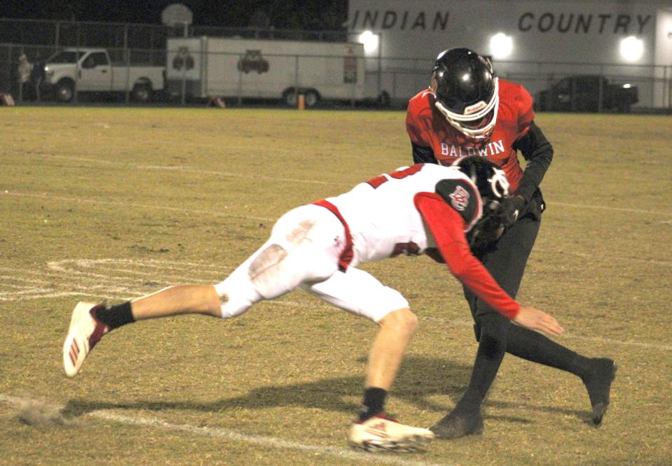 Baldwin receiver Kelvin Brown (19) tries to escape a tackle by Baker County's Kale Crews (22) during the Class 2S regional semifinal in 2022.